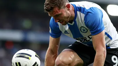 A close-up shot of a Derby County player, with a mixture of determination and disappointment on his face, as he looks...