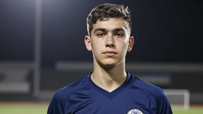 Photorealistic head-and-shoulders shot of a lean 18-year-old goalkeeper in a solid navy blue jersey, smooth fabric texture