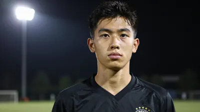 A focused 21-year-old midfielder in a solid black kit, head-and-shoulders