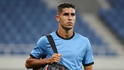 Mid-30s athletic midfielder, lean build, waist-up, solemn expression, eyes glistening, wearing a plain sky-blue shirt...
