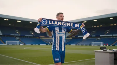 Tommy Watson, mid-30s, athletic build, wearing a plain navy-blue Brighton shirt and white shorts, sprinting with the ball...