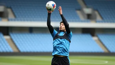 A close medium shot fills the frame with a forward, late twenties, athletic build, leaping to head a ball in mid-air at...